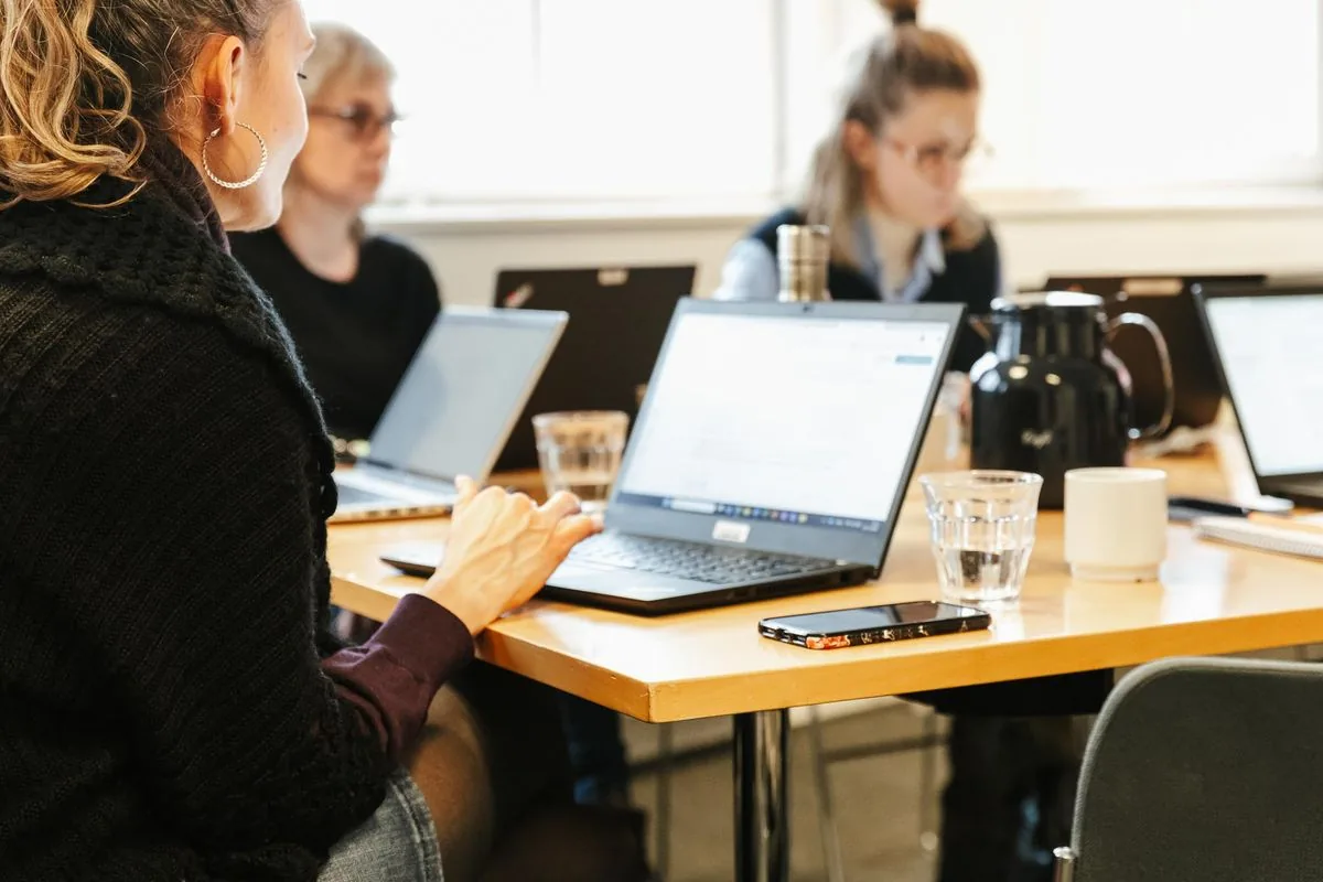 Kursister arbejder ved laptops med research og Claude kursus øvelser i et workshoplokale