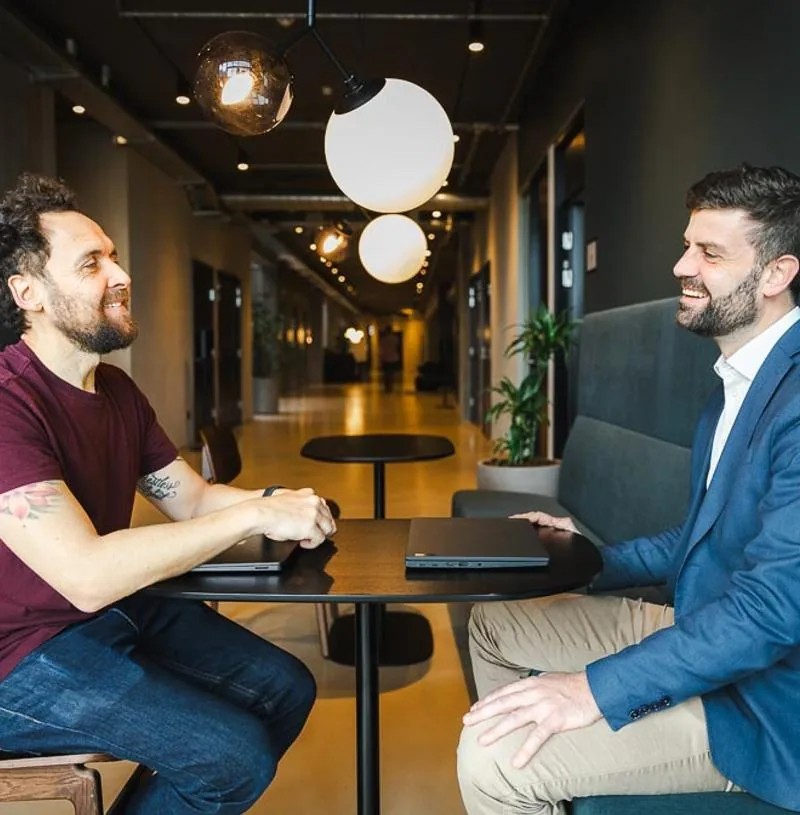 Jacob taler med samarbejdspartner i mødelounge om AI Act konsulent hjælp og compliance