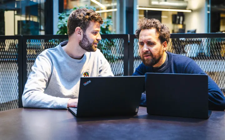 Jacob og Frederick vurderer AI tools ved laptops i et møde hos HverdagsAI om budget og værdi.