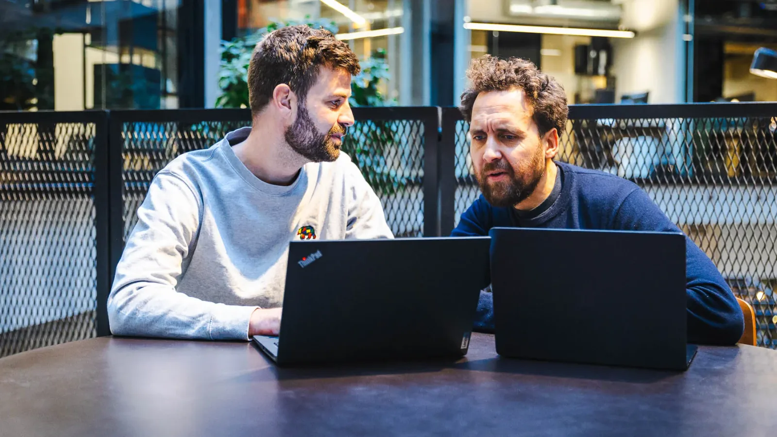 Jacob og Frederick vurderer AI tools ved laptops i et møde hos HverdagsAI om budget og værdi.
