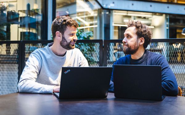 To undervisere vurderer værktøjsvalg på laptops i et mødelokale til AI automation.