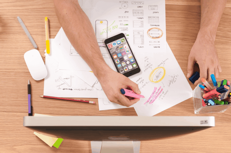 Billede af hænder der arbejder på et blueprint med en mobiltelefon for at vise proof of concept omkring AI-agenter og automation.
